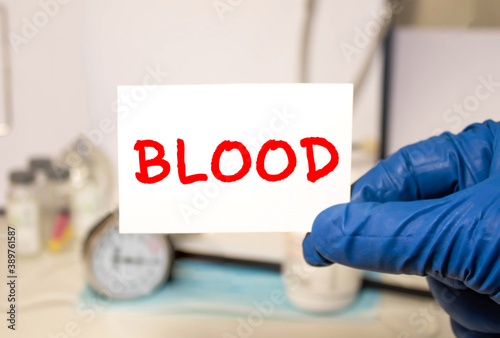 The doctor holds a card with the text BLOOD. Medical concept