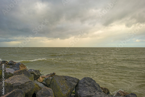 Dike under dark grey rain clouds in a stormy autumn, Almere, Flevoland, The Netherlands, November 2, 2020 
