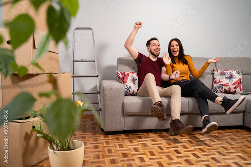 Happy couple on sofa celebrating moving to a new home 