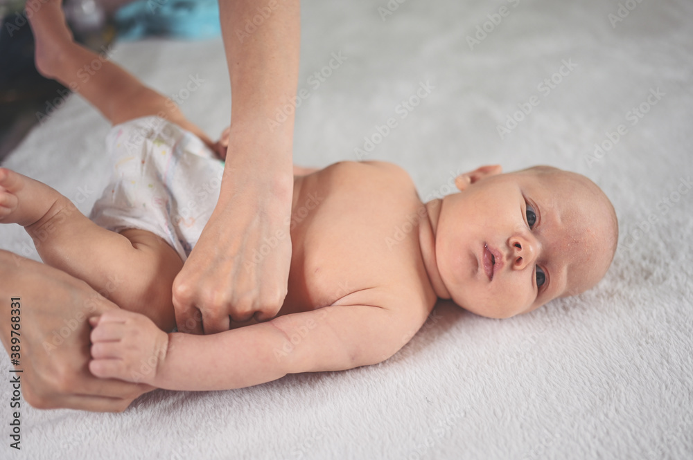 Mother is changing diaper for cute emotional funny newborn little infant baby boy laying in crib Mother is changing diaper for cute emotional funny newborn little infant baby boy laying in crib