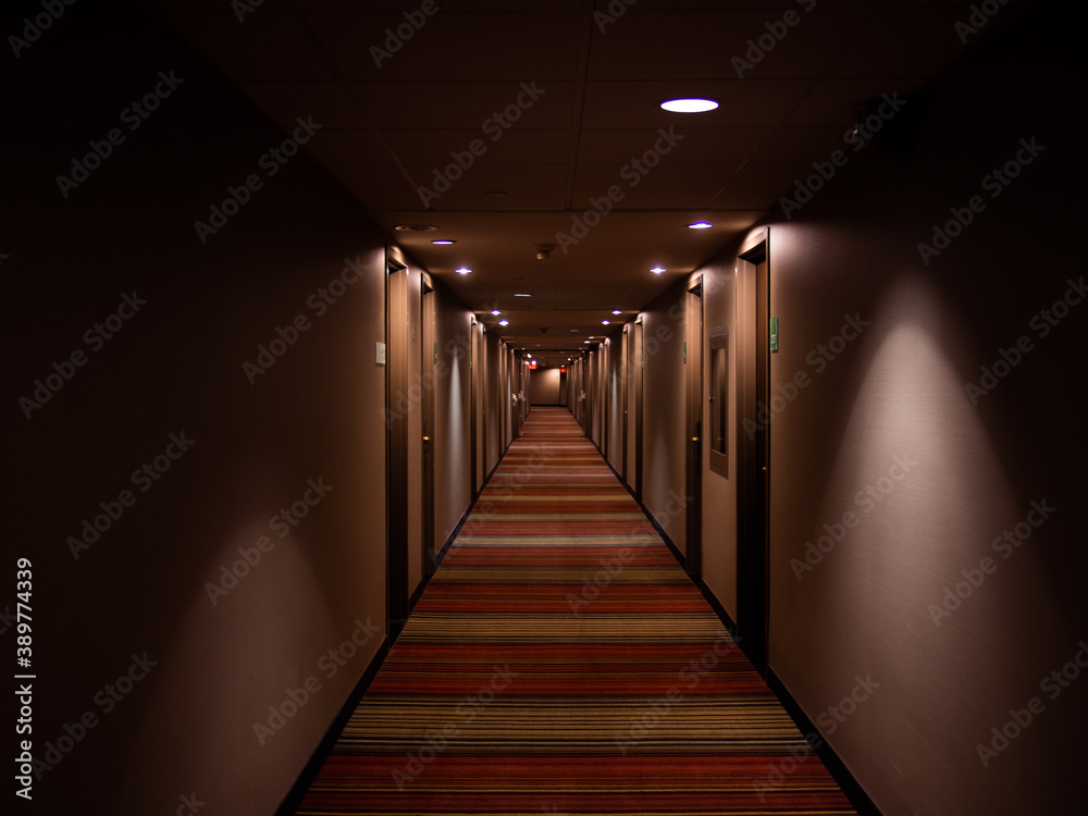 Long corridor avec plusieurs portes et lumières au plafond Long corridor avec plusieurs portes et lumières au plafond