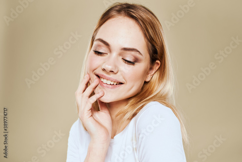 Cheerful blonde gesturing with her hands studio beige background