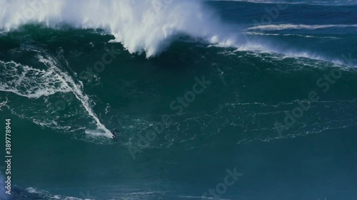 Slow motion of a big wave surfer riding a crazy big monster wave in Nazaré, Portugal. Nazaré is a small village in Portugal with the biggest waves in the world.