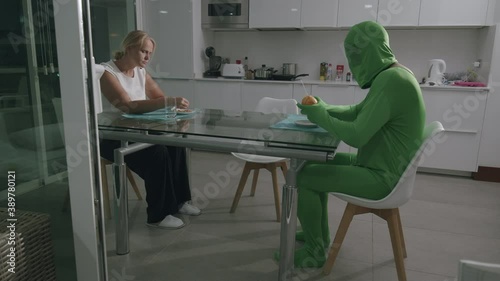 Man wearing a green costume and sitting at the table at home. Communication troubles with his wife
