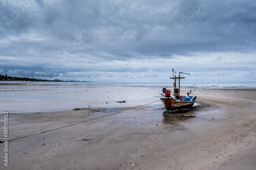 Wooden fishing boat - Fisherman's long-tail boat is docked on the beach during the sunset on the sea. Huahin - Pranburi Prachuap Khiri Khan Province.