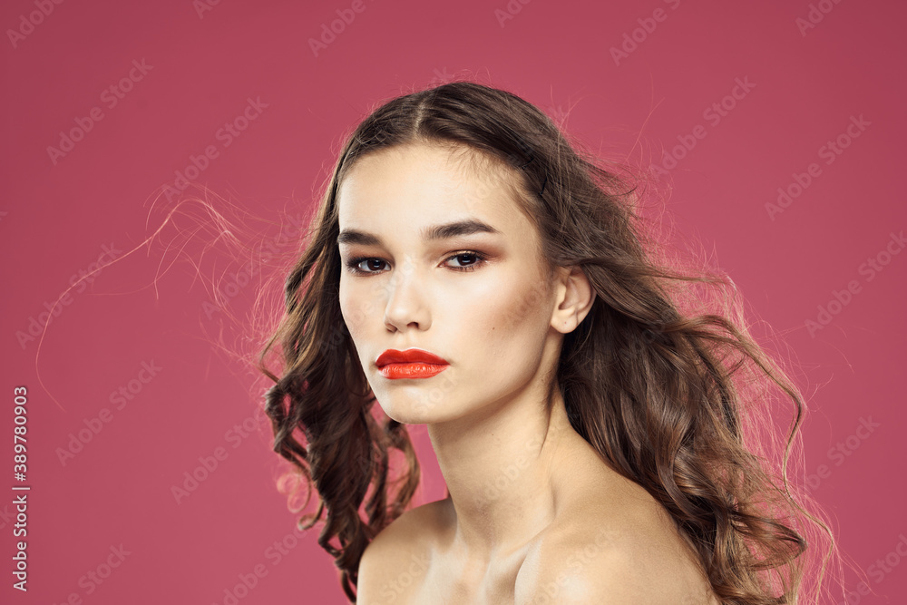 Beautiful brunette woman with makeup on her face on a pink background naked shoulders Beautiful brunette woman with makeup on her face on a pink background naked shoulders