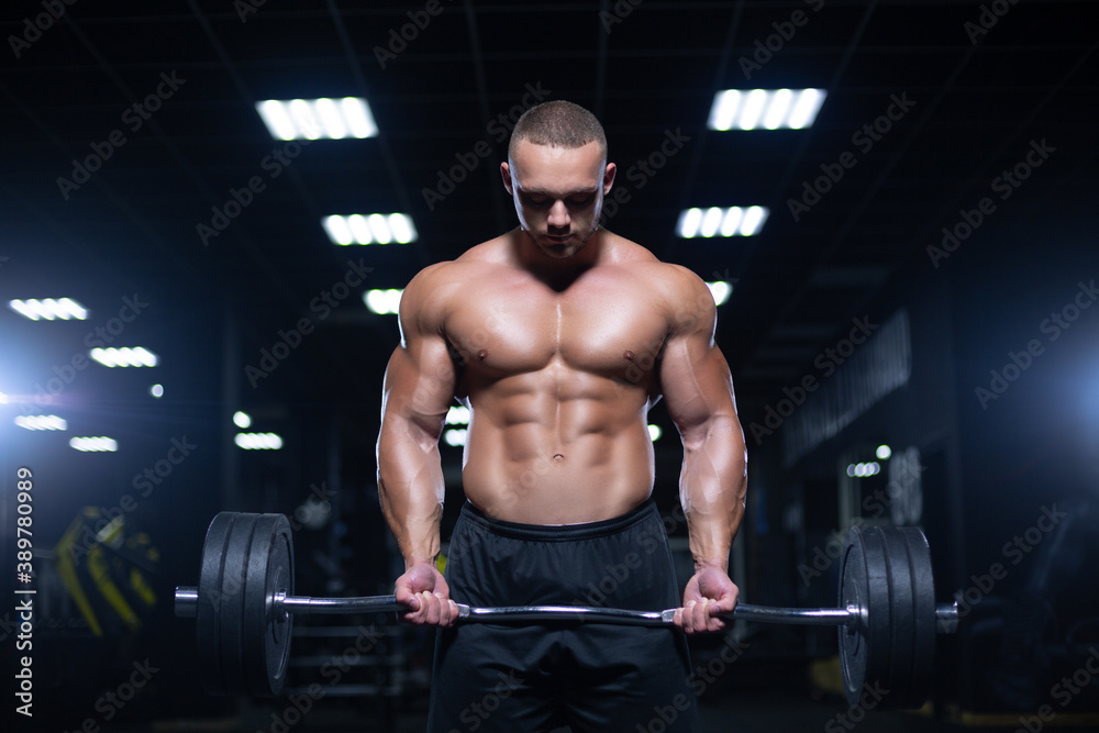 Muscular sexy bodybuilder is working out doing weight lifting of the barbell in gym Muscular sexy bodybuilder is working out doing weight lifting of the barbell in gym