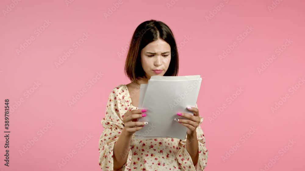 Distressed angry woman holding files papers, scatters them isolated on pink background. Pretty girl checks documents, utility bills. Distressed angry woman holding files papers, scatters them isolated on pink background. Pretty girl checks documents, utility bills.