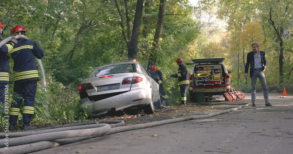 Man walking near firemen extinguishing fire on car Man walking near firemen extinguishing fire on car