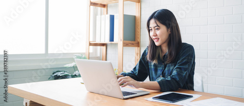 Graphic designer using graphics tablet happy smiling Asian woman freelance worker using computer laptop technology designing innovation creative ideas planning brainstorming working home modern office