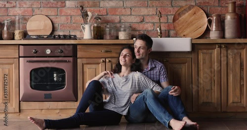 Couple in love relaxing sit on warm floor with underfloor heat system stay at home on weekend. Romantic harmonic relations, bank loan for family, happy clients of kitchen remodelling services concept