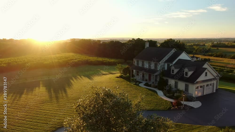Gorgeous aerial establishing shot of large home during summer sunrise. Beautiful house in rural America set among nature and agriculture. Colorful scenery.