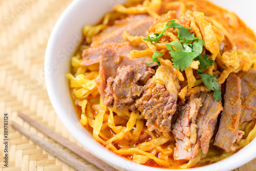 Northern Thai food (Khao Soi), Spicy curry noodles soup with beef in a bowl and chopsticks, Close up