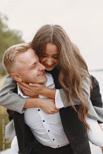 Cute couple in a park. Lady in a gray coat. People on the pier.