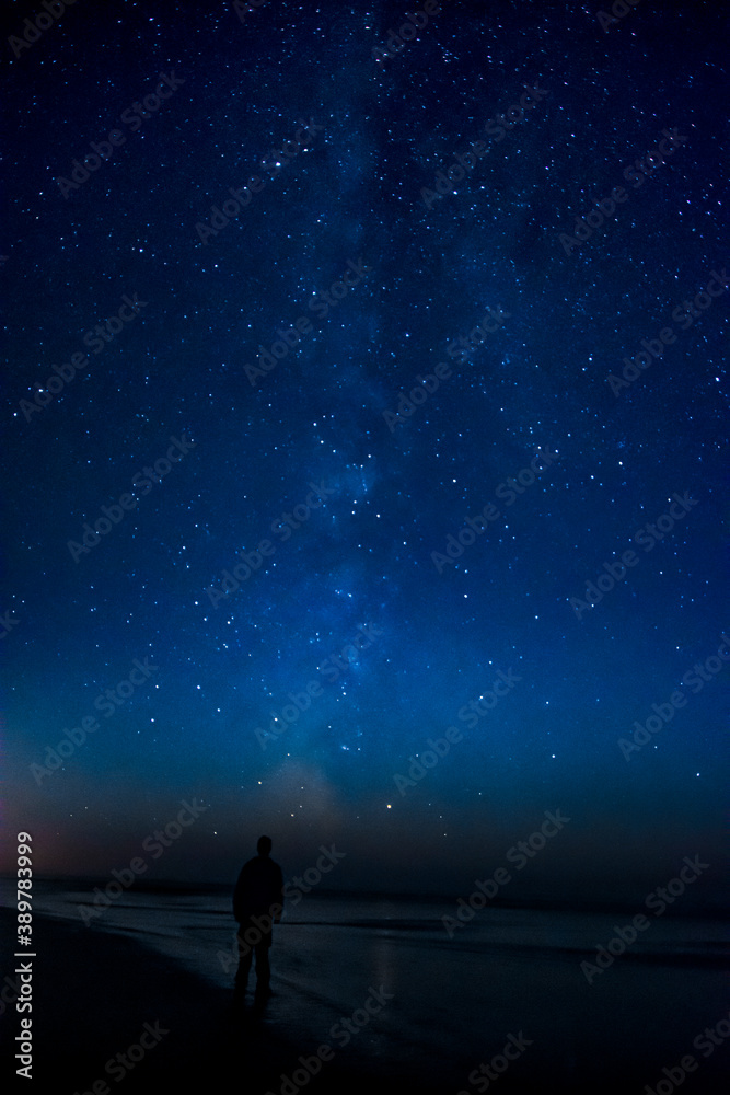 Adventurous man watching the stars on a beach at night. 