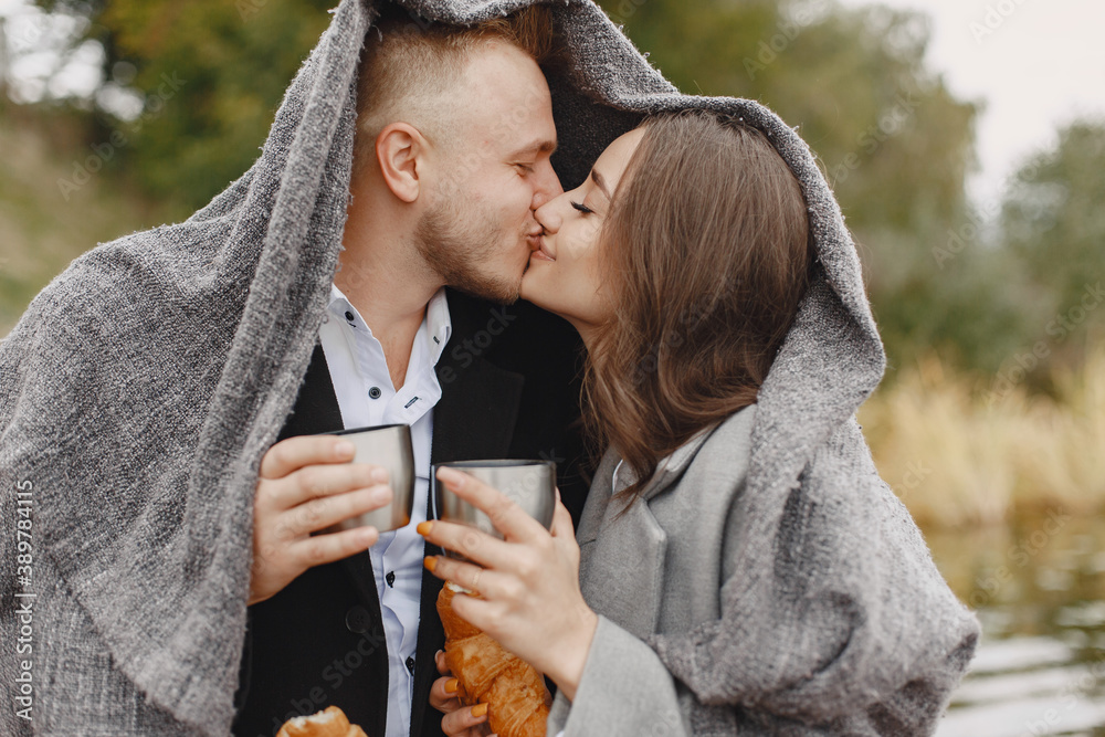 Cute couple in a park. Lady in a gray coat. People with a thermos and croissant. Cute couple in a park. Lady in a gray coat. People with a thermos and croissant.