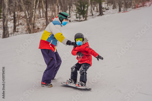 Snowboard instructor teaches a boy to snowboarding. Activities for children in winter. Children's winter sport. Lifestyle © galitskaya