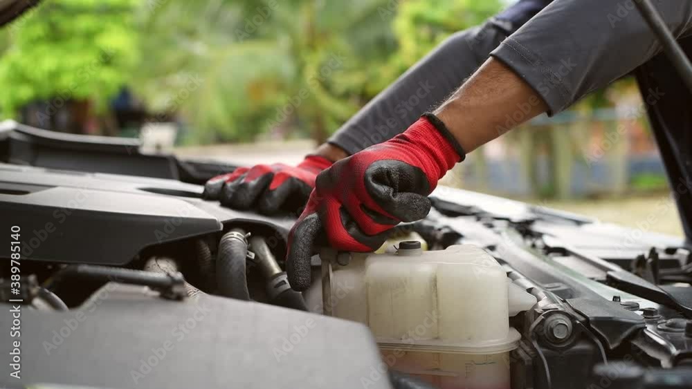 Car mechanic under repairing car open hood checking oil motor level for refill and clean in car garage service. Car mechanic under repairing car open hood checking oil motor level for refill and clean in car garage service.