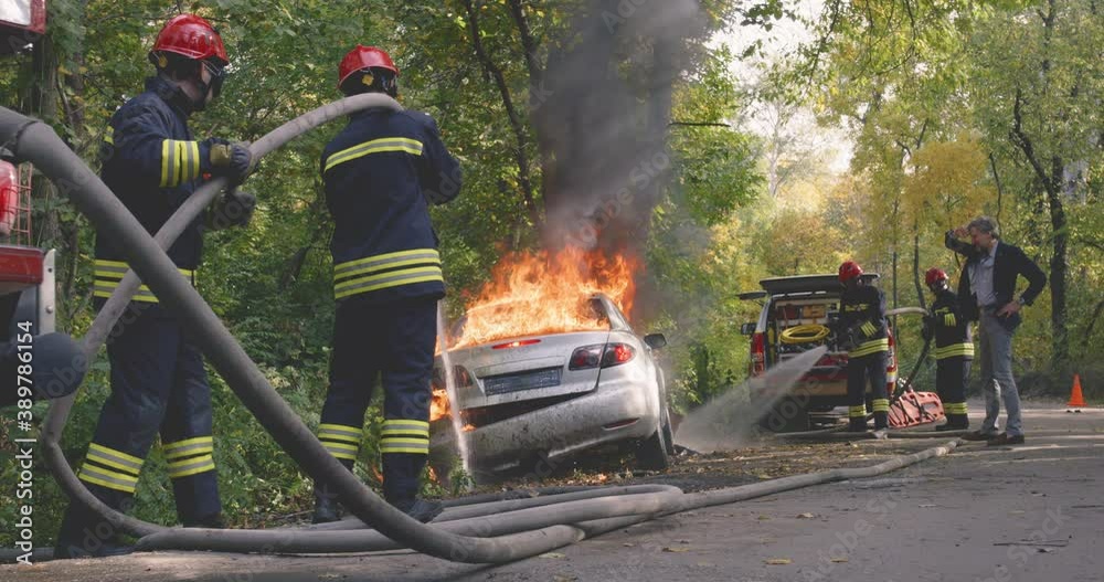 Man watching firemen saving car from fire
