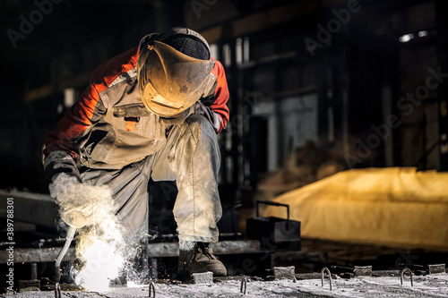 Tableau sur toile A young  man welder in  uniform, welding mask and welders leathers, weld  metal