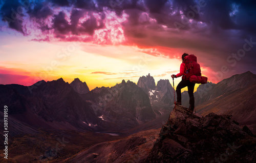 Woman Standing on Rocks looking at Scenic Mountain Peaks and Valley, Fall in Canadian Nature. Dramatic Twilight Sky Adventure Composite. Bacground Landscape, Tombstone Territorial Park, Yukon, Canada. photo