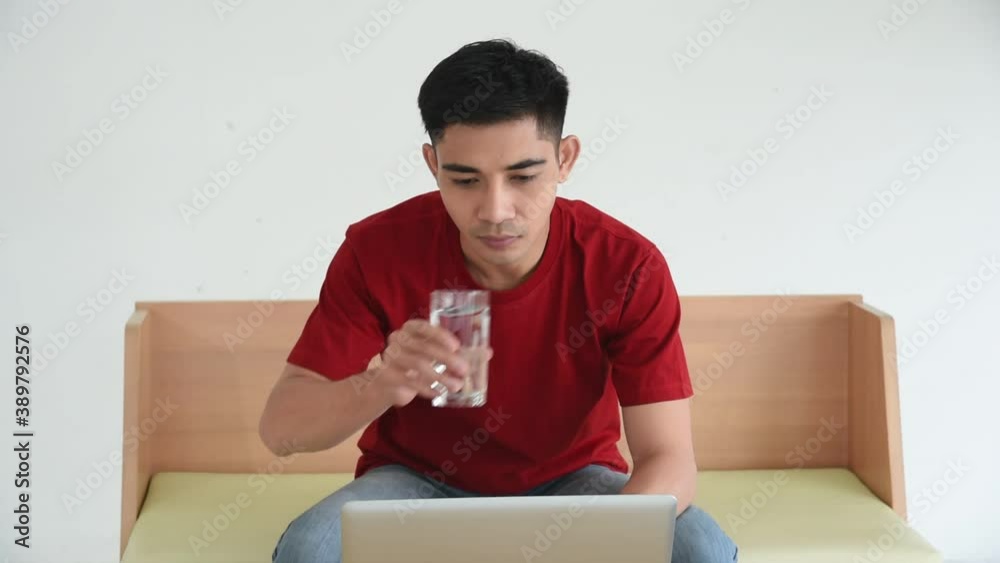 Young man in red casual outfit having a pain from wearing braces in living room Young man in red casual outfit having a pain from wearing braces in living room