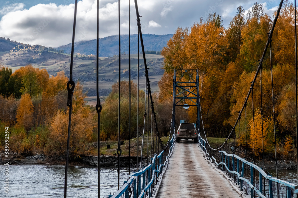 Obraz premium Offroad suv cross the river through vintage rustic suspension bridge. River crossing concept. Old rope bridge. Travel, journey, adventure concept.