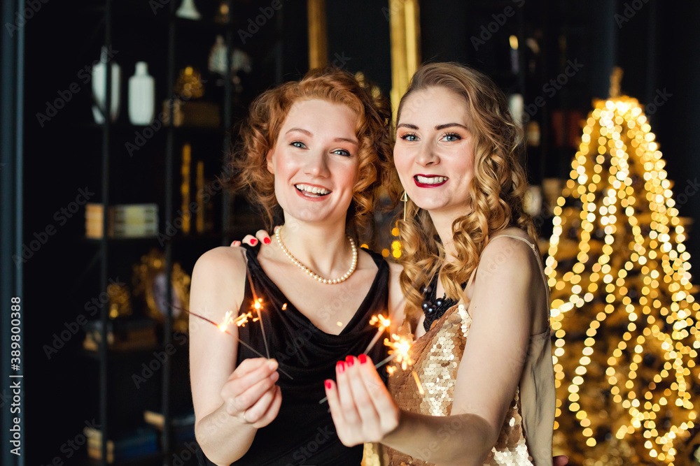 Sparklers in the hands of two beautiful women, Christmas lights and gifts. Gold Christmas decoration. Happy New Year. Sparklers in the hands of two beautiful women, Christmas lights and gifts. Gold Christmas decoration. Happy New Year.