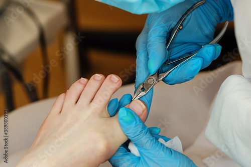 Master chiropody removes the cuticle. Cuticle treatment is one of the stages of processing the cuticle. Woman legs at pedicure procedures. Spa. Concept body care. Clinic Podiatry Podology. photo