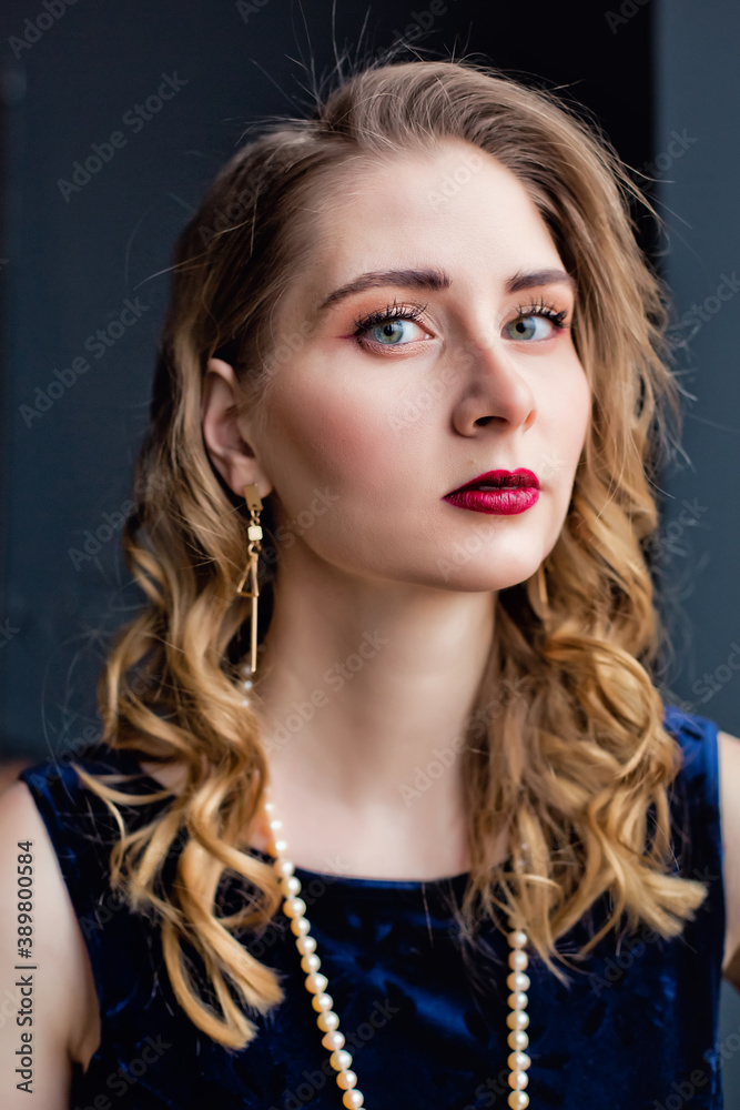 A beautiful women in a blue velvet dress and pearl beads near the window. A beautiful women in a blue velvet dress and pearl beads near the window.