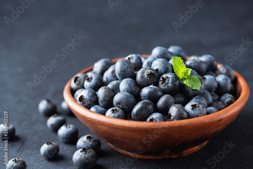 Blueberries in bowl over black background. Organic juicy blueberries closeup view