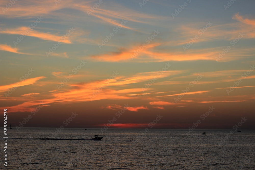 a boat sails in the black sea against a beautiful sunset