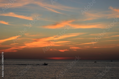 a boat sails in the black sea against a beautiful sunset © Arina Popkova