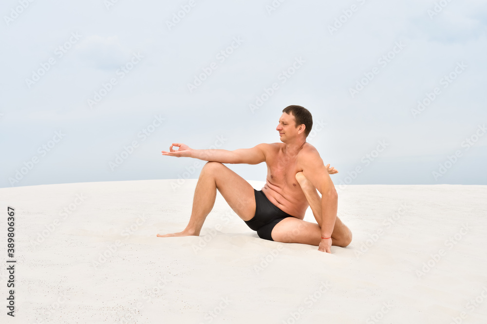 Man sitting on sand in yoga pose on the beach Man sitting on sand in yoga pose on the beach