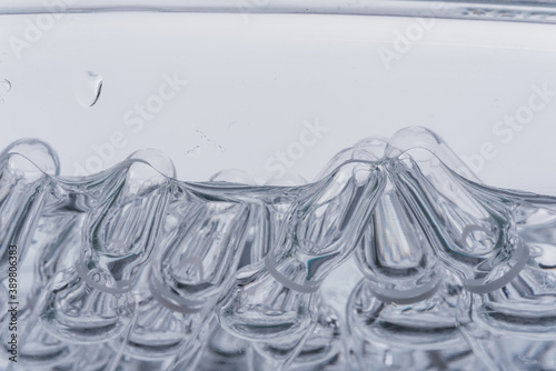 Glass medical ampoule vial for injection. Medicine is liquid sodium chloride with of aqueous solution in ampulla. Close up. Bottles ampule multicolor on background color and water. Human plasma.