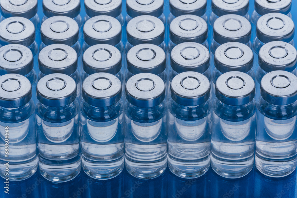 Glass medical ampoule vial for injection. Medicine is liquid sodium chloride with of aqueous solution in ampulla. Close up. Bottles ampule multicolor on background color and water. Human plasma. Glass medical ampoule vial for injection. Medicine is liquid sodium chloride with of aqueous solution in ampulla. Close up. Bottles ampule multicolor on background color and water. Human plasma.