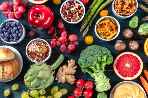 Vegan food variety. Fruit and vegetables, legumes, nuts, mushrooms, rice, pasta, healthy organic products, shot from the top on a dark background