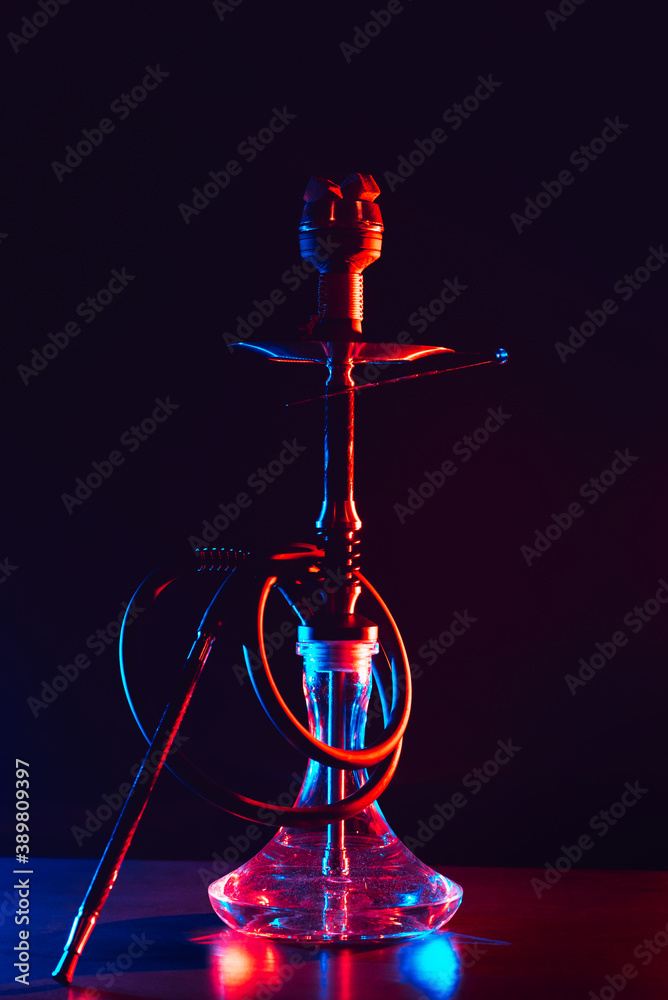 glass hookah with a metal bowl with hot coals on a black background on a table