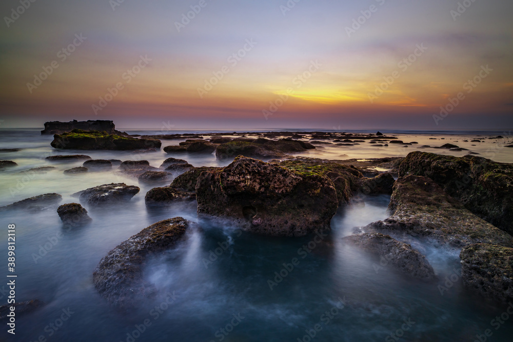 Obraz premium Amazing seascape. Landscape background. Beach with rocks and stones. Low tide. Motion water. Slow shutter speed. Soft focus. Mengening beach, Bali, Indonesia