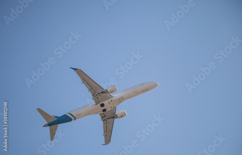 White plane flies in the sky. Bottom view. Takeoff and landing. Arrival and departure. Passenger plane isolated on blue background. Airplane flying. Travel by air transport. Copy space.