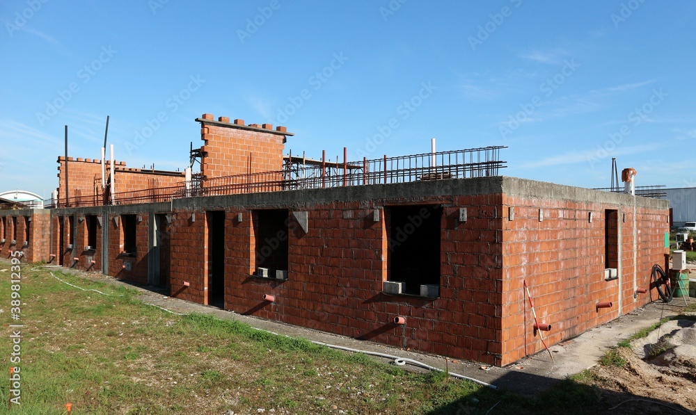 House under construction with only the first floor finished and the bricks exposed. Copy space. House under construction with only the first floor finished and the bricks exposed. Copy space.
