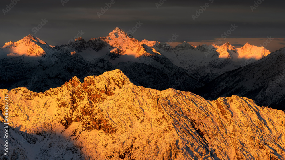 Strong morning light that shines in the morning on the alp mountains that are covered with snow. Orange glow.