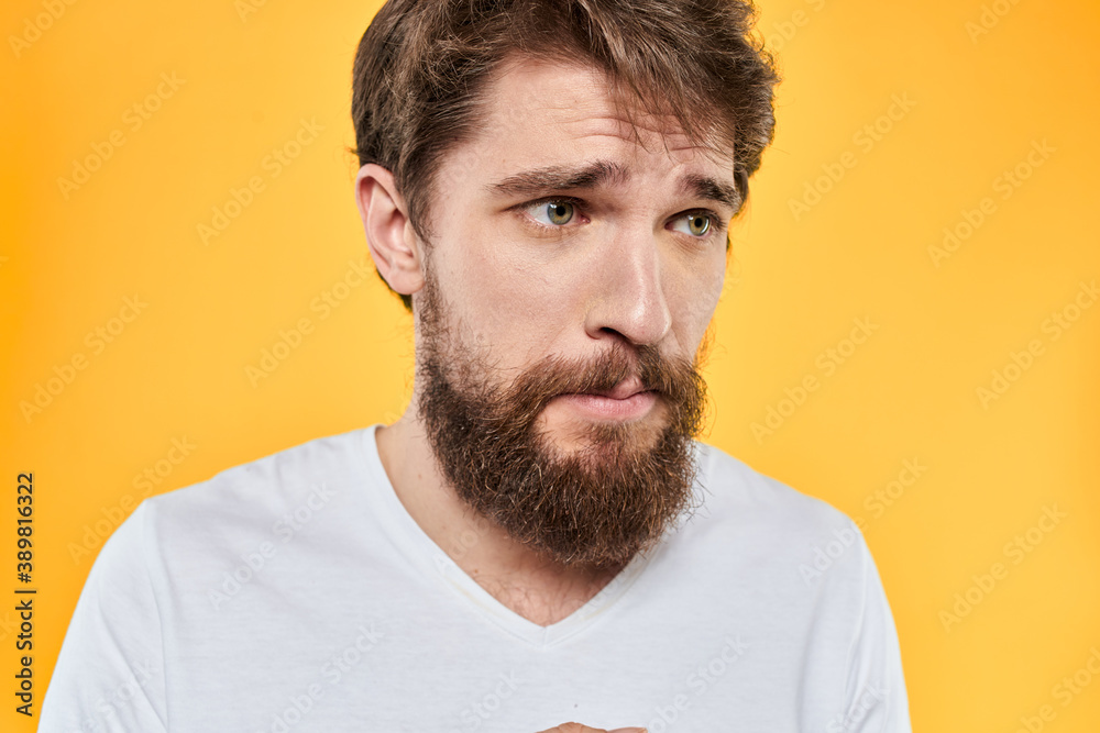 Fototapeta premium Man with emotional expression white t-shirt close-up studio yellow background