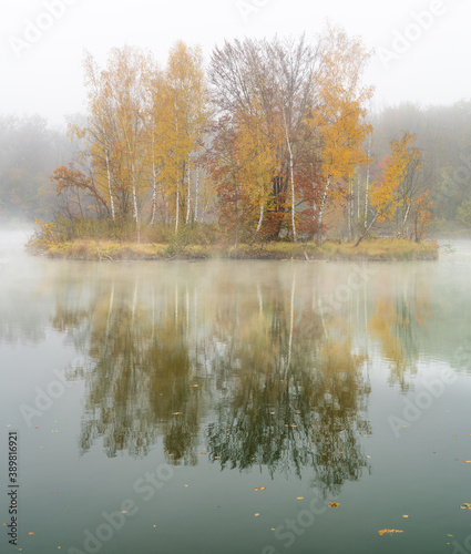 Small island in autumn colors with morning mist, fog