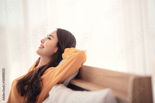 Relaxed young asian woman enjoying rest on comfortable bed, calm attractive girl relaxing and breathing fresh air in home, copy space.