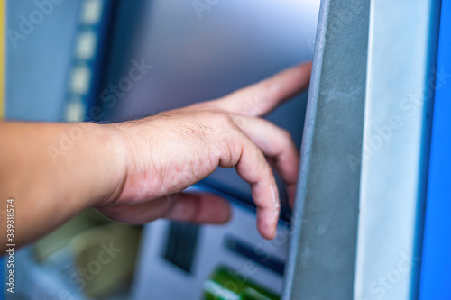 Close-up of man (wearing blue jean), using credit card to withdrawing money from ATM machine. Finance and business concept