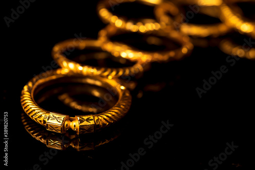 Traditional Indian Gold Jewelry. Expensive Gold bangle Jewelery on black background for diwali, dhanteras celebration shopping, gifting offer. Closeup of gold ornaments for festive occasion.