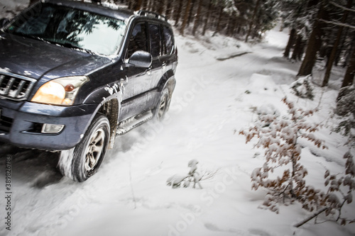 Motion blurred image of a big suv car going fast on a snow covered forest road © lightpoet