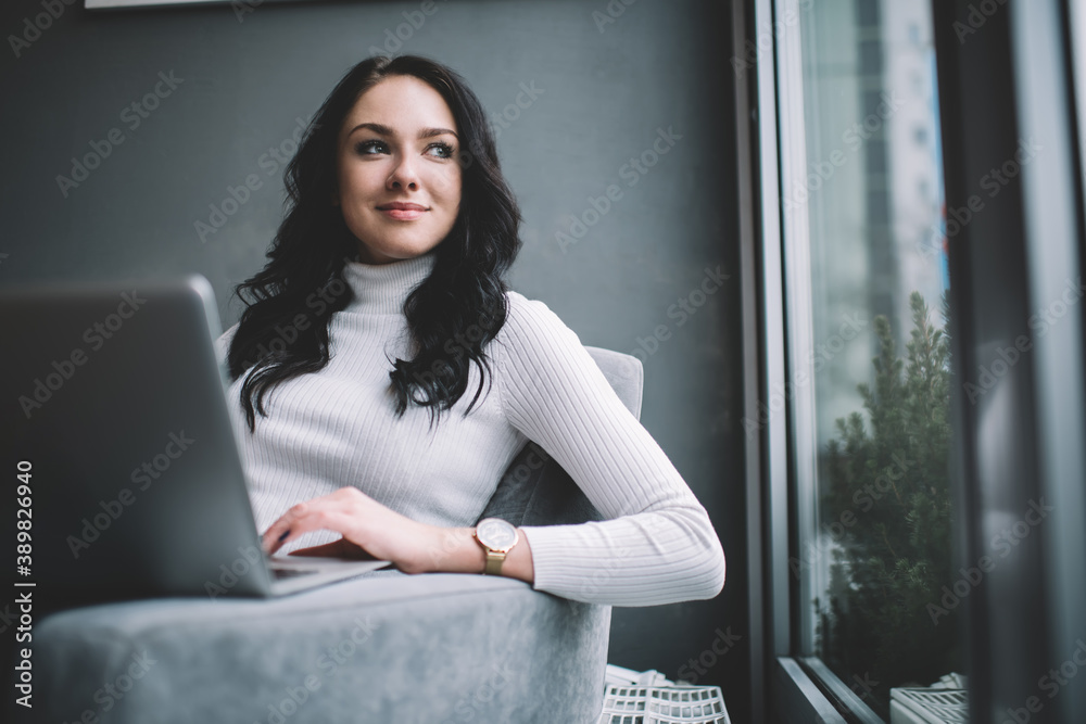 Smiling woman browsing laptop in armchair Smiling woman browsing laptop in armchair