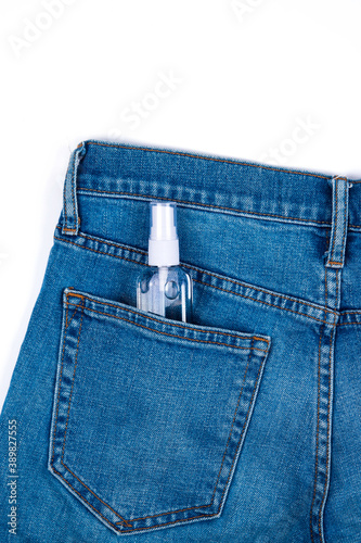 Top view of antibacterial antiseptic spray for hands sanitizer in bottle in jeans pocket isolated on white background with copy space. Prevention against virus, bacteria or coronavirus